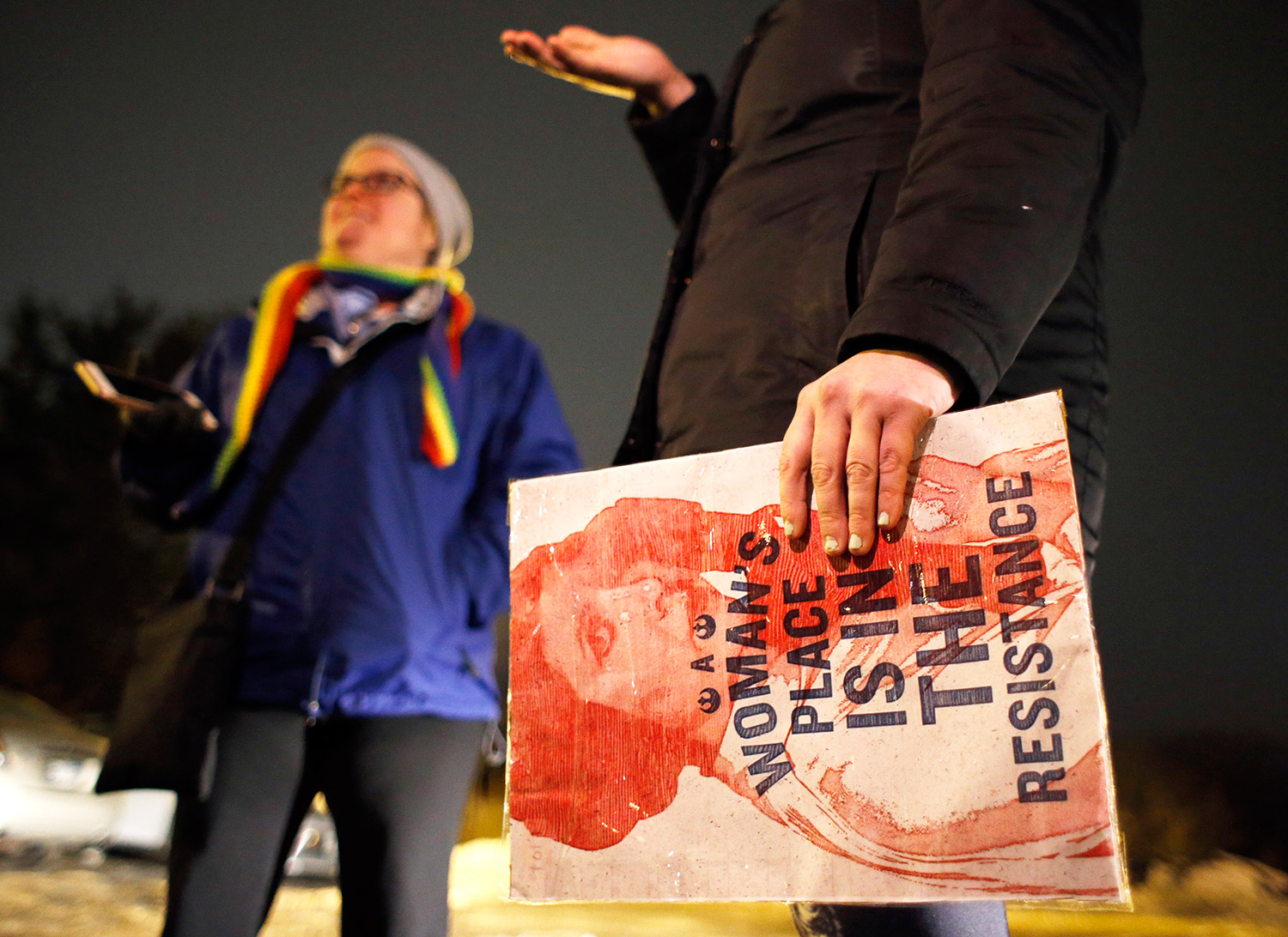 Norita Boynton holds a protest sign near the Portland Transportation Center on Friday night while waiting to board a bus bound for Washington, D.C., for Saturday's Women's March. Tara LaFreiere, left, is a volunteer organizer.