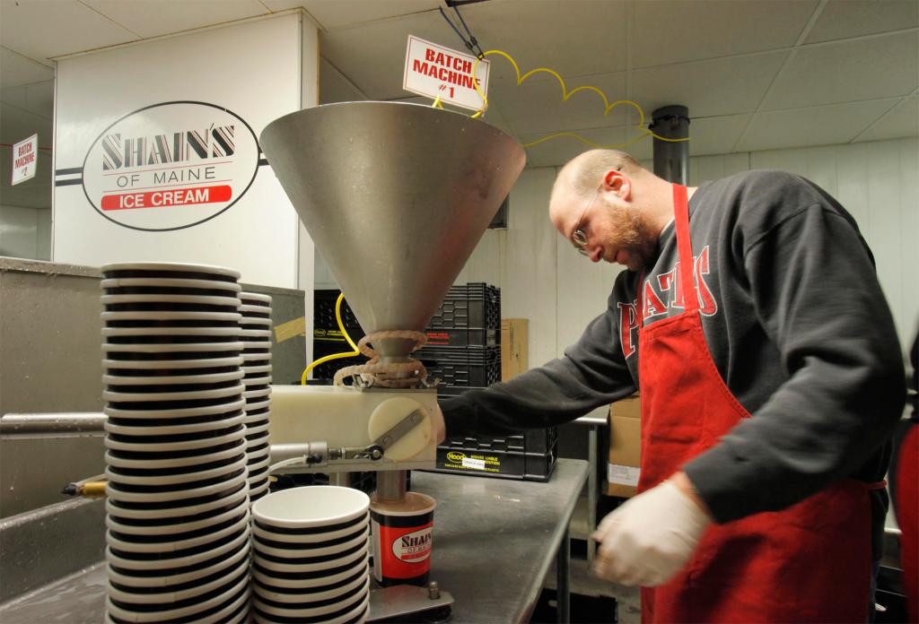 Reporter Ray Routhier fills a container with chocolate ice cream at Shain’s of Maine in Sanford last week. After two pushes of the trigger, the quart is filled. The “Shain’s” name on the lid has to face the front of the container.