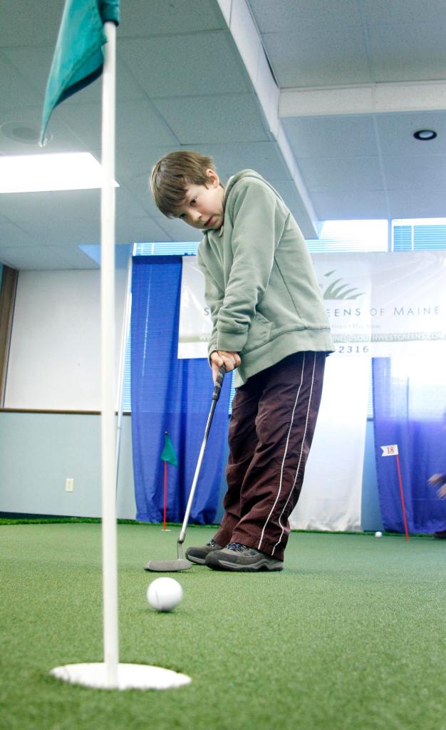 Isaiah Anderson, 10, of South Portland practices his putting as part of “adjusting his accuracy” during the golf expo at the Holiday Inn by the Bay in Portland. “I can’t make the close shots so much,” the fifth-grader said.