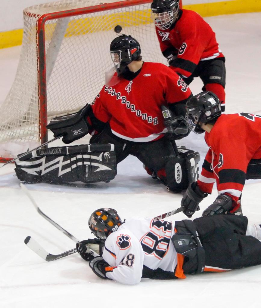 Gregory Rec/Staff Photographer: Biddeford's Derek Reny falls to the ice after putting a shot past Scarborough goalie Matt Mayo in the second period, scoring Biddeford's third goal of the quarterfinal boys hockey game at the Biddeford Ice Arena on Tuesday, February 23, 2010.
