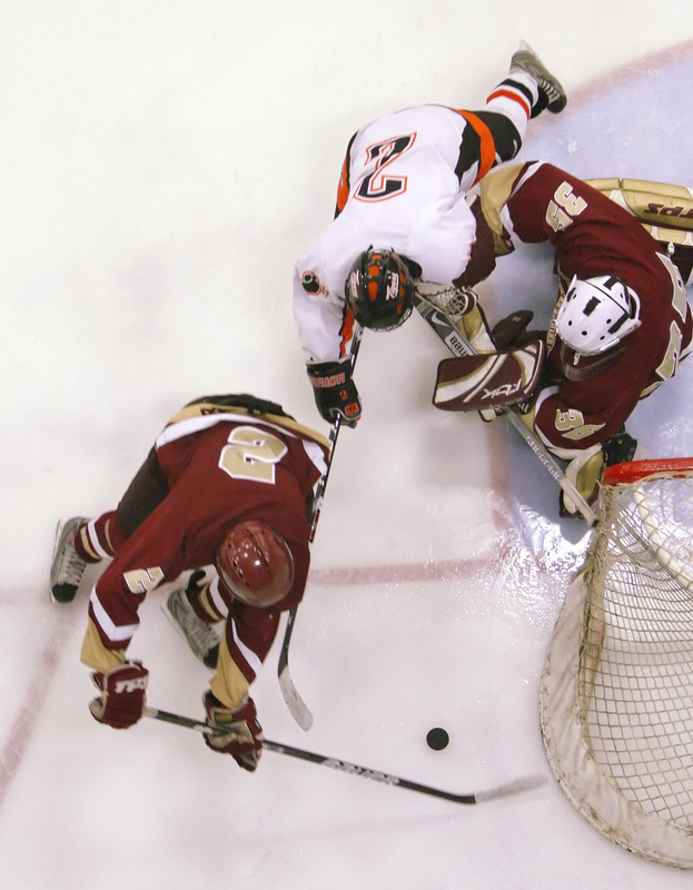 Bryan Dallaire of Thornton Academy attempts to keep the puck away from goalie Rick Hebb and a charging Brady Fleurent of Biddeford during their game at Lewiston.