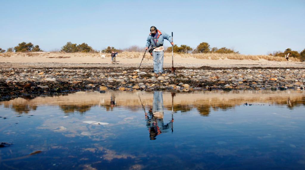 Paul Morse of West Baldwin uses a metal detector Friday to search for valuables among the rocks that have been exposed by erosion at Scarborough Beach.