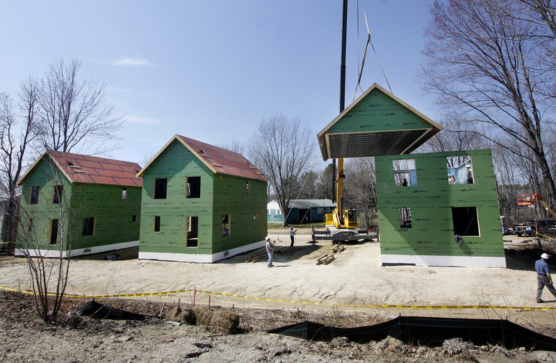 Workers use a crane to position the roof on the last of three steel houses that Habitat for Humanity is building on Bremen Street in Westbrook on Wednesday. The homes are pieced together at the site by using pre-manufactured framing panels; these were made by Porter Panel and Truss in Portland.