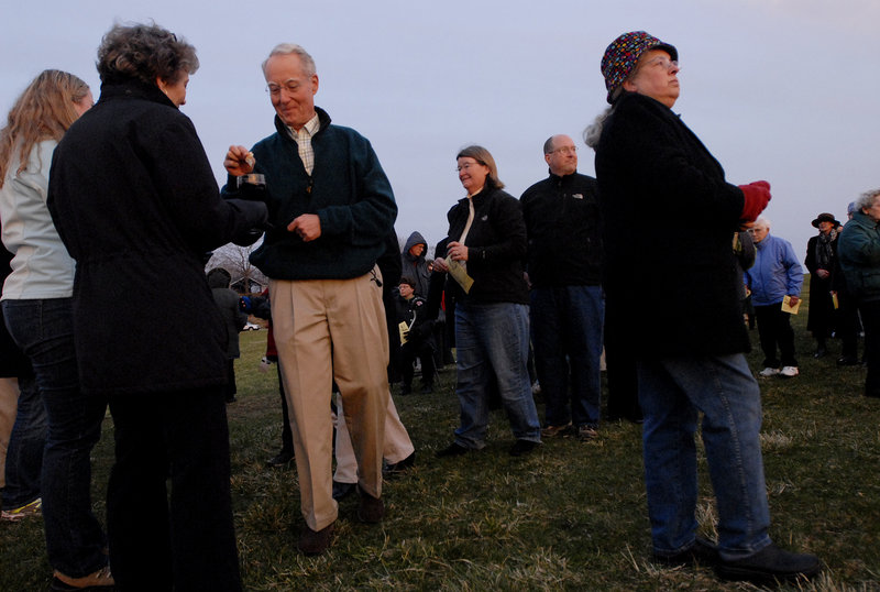 Kathy Sahrbeck of Cape Elizabeth looks toward the rising sun after receiving Communion as Scott Berry is administered the sacrament at an Easter service at Fort Williams Park on Sunday.