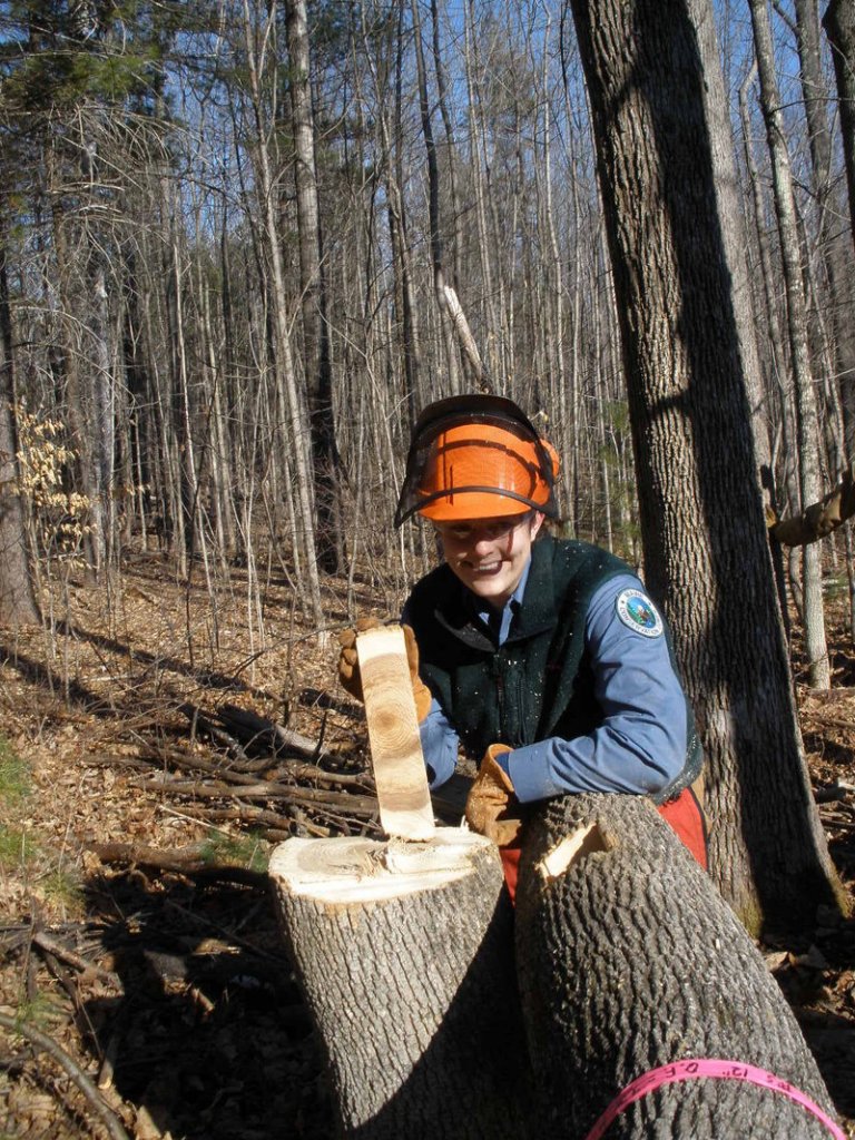 Krista Rogers of West Bath stands beside the stump of the first tree she ever felled using a chain saw. The work is being done as part of a 10-week Trail Training Academy that Rogers is attending.