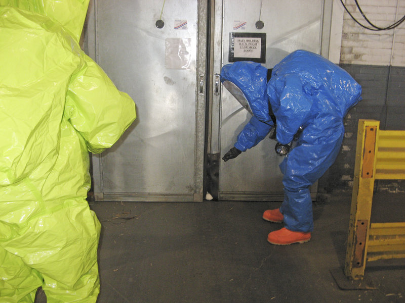 Portland Lt. Mike Nixon uses a sensor to check ammonia levels behind a door leading to the room at Americold Logistics where a large cooling unit fell from the ceiling Jan. 22. Steve Brezinski of the Maine DEP stands by as he waits to enter the room.