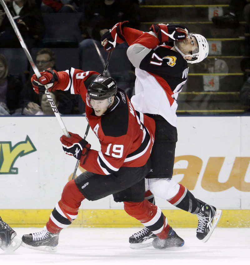 Derek Whitmore, right, recoils after being hit in the face by the stick of Lowell's Brad Mills during Saturday's game at the Civic Center. The Pirates fell out of contention for the Atlantic Division title, losing 5-2.