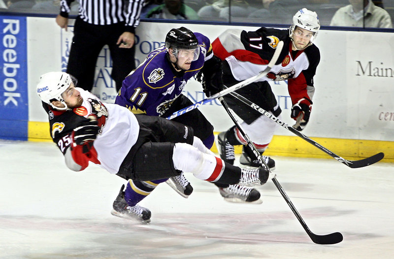 Mark Mancari of the Pirates is upended by Manchester's Trevor Lewis as Marc-Andre Gragnani looks on. Portland will try to pull even in the best-of-seven first-round series when it hosts Game 2 tonight.