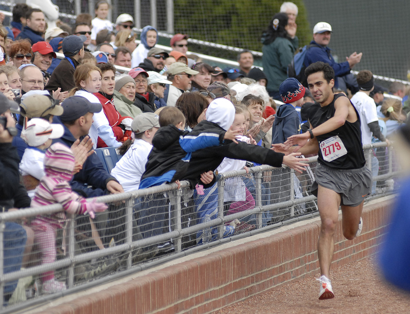 Louie Luchini of Ellsworth, the first finisher of Sea Dogs Mother's Day 5K gets high fives from spectators as he approaches the finish line today