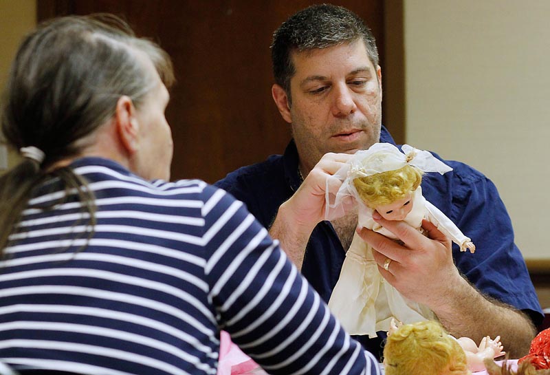 Bruce Zalkin reviews four dolls brought in by Margaret LaFlamme of Cape Elizabeth, left. Zalkin, who runs the Antique Toy and Doll Buying Show, offered her $150 for the dolls, but LaFlamme turned him down. “I’ll keep them a little while longer,” she said.