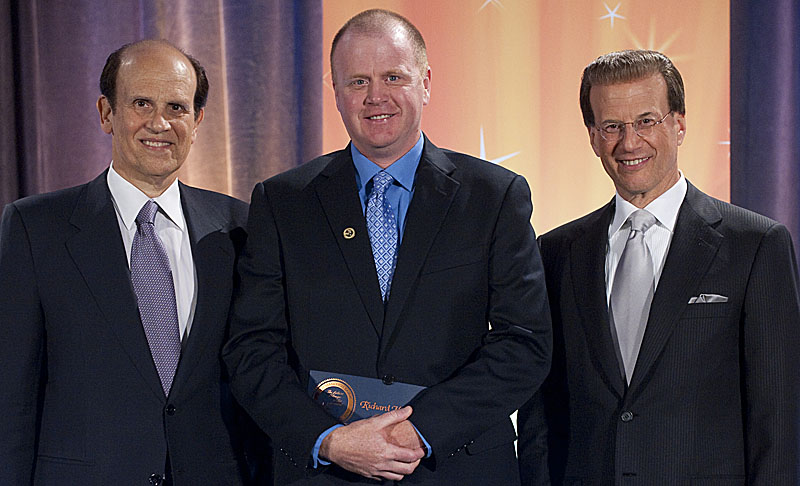 Richard Meserve, a special education teacher at The REAL School, receives $25,000 from Milken Family Foundation Co-Founder Michael Milken, left, and Foundation Chairman Lowell Milken, right, on Saturday.