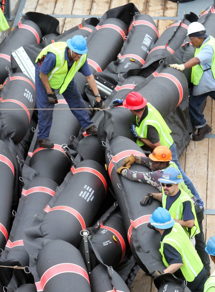 Workers secure inflatable containment booms Friday on the deck of an offshore service vessel in Gulfport, Miss. Maine is among the states prepared to help.