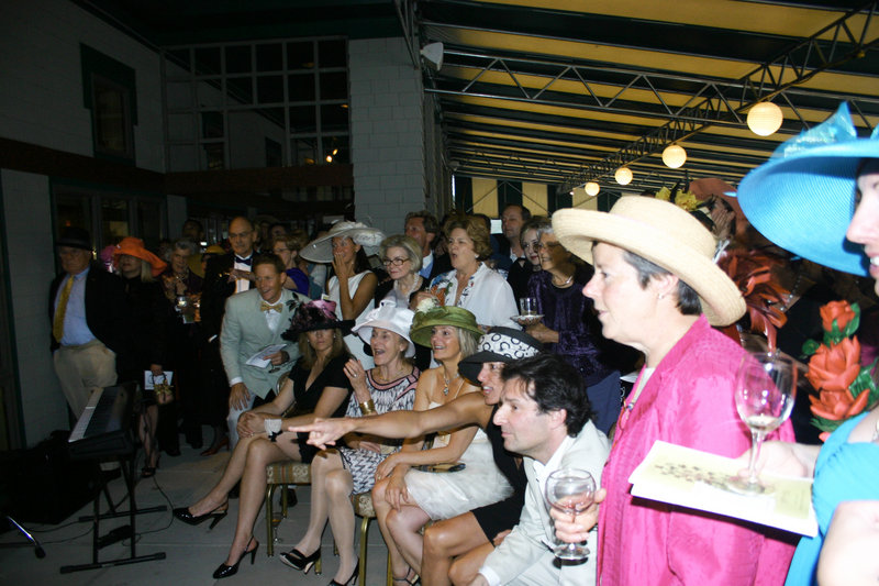 The Mad Hatter Affair centers around the Kentucky Derby, which is broadcast for the partygoers. Here the crowd reacts as Super Saver defies the muddy track and wins the 136th derby.