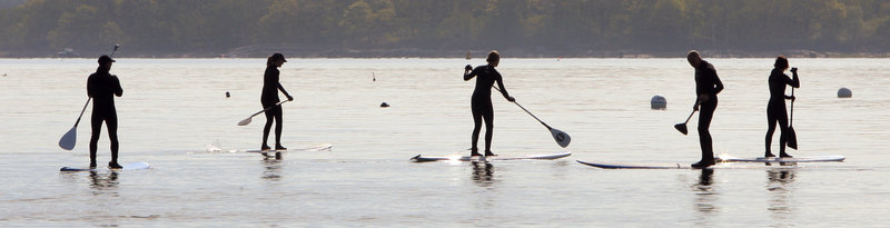People travel by paddleboard across Casco Bay after attending a protest against offshore drilling on East End Beach in Portland on Wednesday.