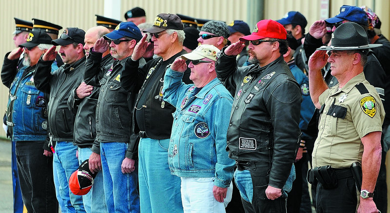 Law enforcement officers and Patriot Guard Riders salute as soldiers move the casket containing Spec. Wade Slack’s remains Friday morning. The group was part of a motorcade that then drove north with the hearse to a funeral home in Waterville.