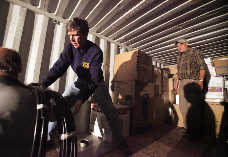 Jim Dawson, left, grabs a roll of cable while Charlie Miller waits to load another box inside a shipping container in Portland on Wednesday. The cargo is bound for the Justinian University Hospital in Haiti, courtesy of Konbit Sante, a Portland group that works with the hospital. Dawson and Miller are with the Portland Rotary Club, which donated money to the effort.