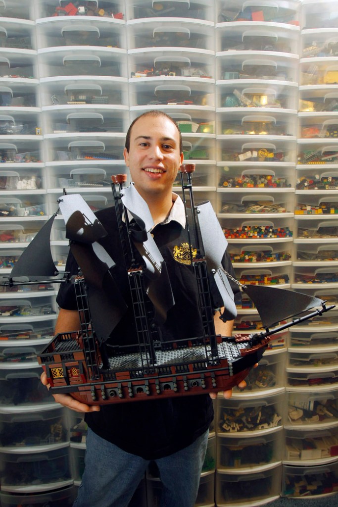 Piccirillo shows off a pirate ship he built from scratch. In the background are dozens of container drawers filled with thousands of Lego pieces that allow Piccirillo uses to build custom projects.