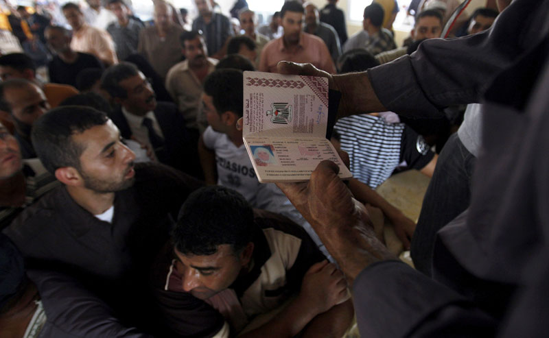 A Hamas border official holds the passport of a Palestinian woman waiting to cross into Egypt through the Rafah border crossing, southern Gaza Strip, today. An Egyptian official says the government is temporarily lifting its blockade of the Gaza Strip to allow aid into the area a day after Israel raided an international flotilla carrying supplies to the Palestinian territory, and killed nine activists.