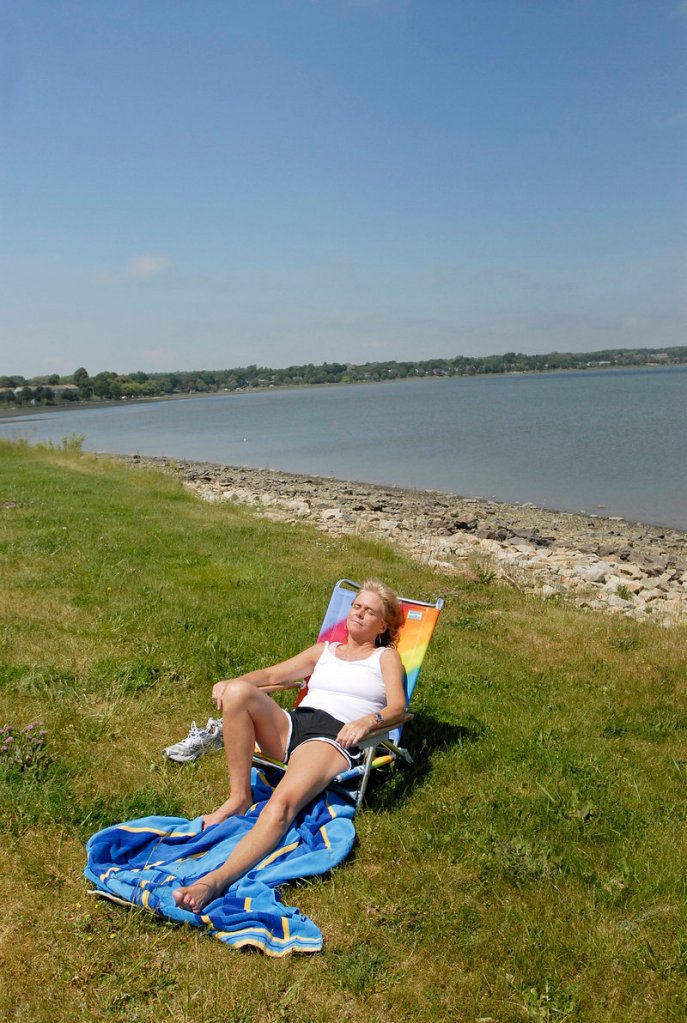 Katie Nee of Scarborough enjoys the sun Wednesday near Back Cove, as a downstream haze in the sky still lingers from the wildfires in Quebec.