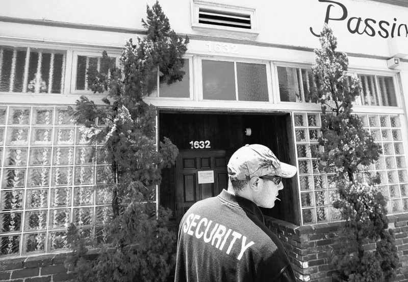 A security guard who declined to give his name stands outside House of Kush, a closed medical marijuana shop, Monday in the Eagle Rock area of Los Angeles.