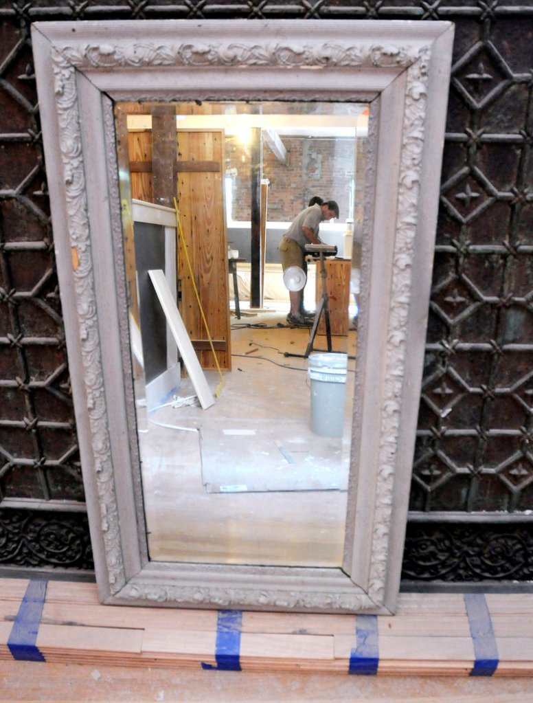 Tom Munroe is reflected in an old mirror as he finishes tables for Havana South, a new restaurant on Wharf Street in Portland. The restaurant is filled with antiques collected by owner Michael Boland, such as this mirror that came from a house on Danforth Street.