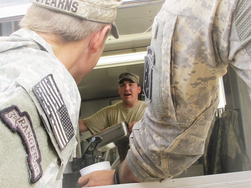 Spc. Jeffrey Pelletier of Waterville, who prepares up to 500 meals a day for Bravo Company, talks with fellow soldiers while cooking.