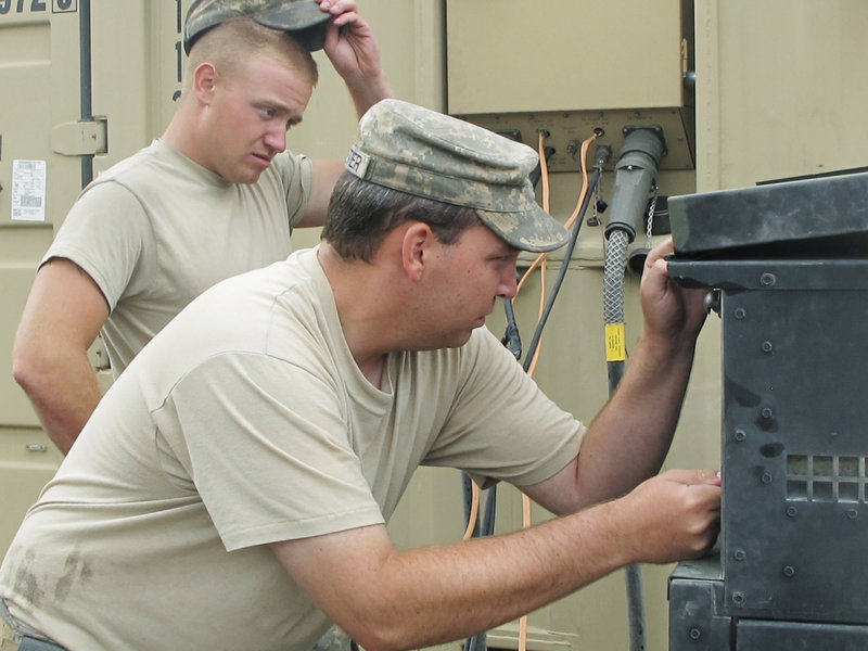 Spc. Jeffrey Pelletier of Waterville, foreground, and Pfc. Kevin Beal of Machias work on a faulty generator that gave out halfway through dinner preparations Wednesday for Maine Army National Guard troops at Combat Outpost Dand Wa Patan in Afghanistan. Moments later, they fired up the barbecue grill.