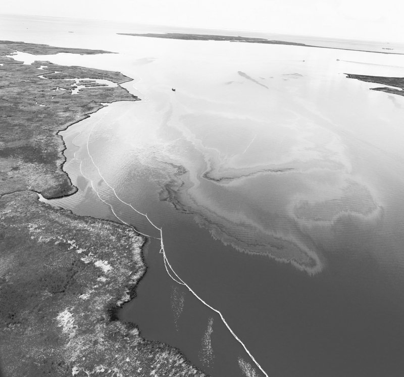 Small boats string boom to keep the BP oil slick from reaching sensitive areas on the Louisana coast. Red tape has left Maine-made boom stranded in Auburn.