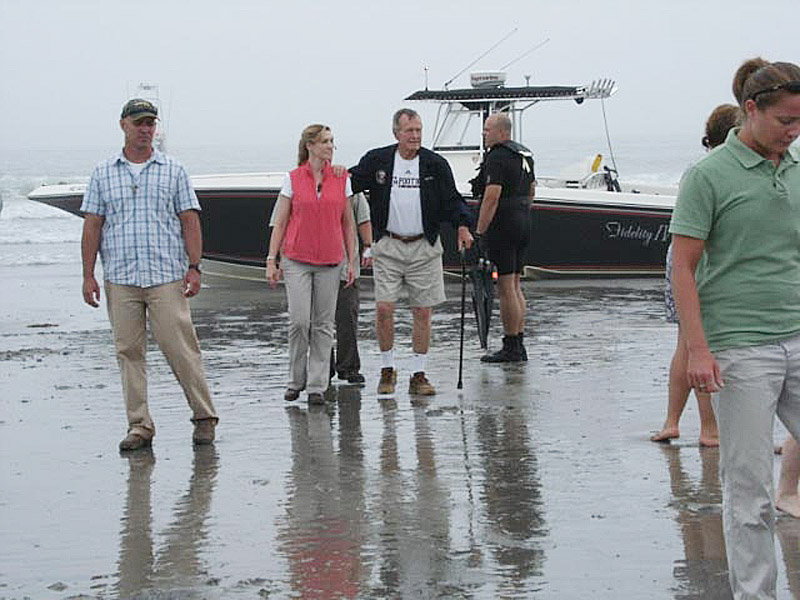 Former President George H.W. Bush and some family members walk away from The Fidelity IV as it sits stranded on Gooch's Beach. Hours later, his staff moved the boat to its dock in Kennebunkport.
