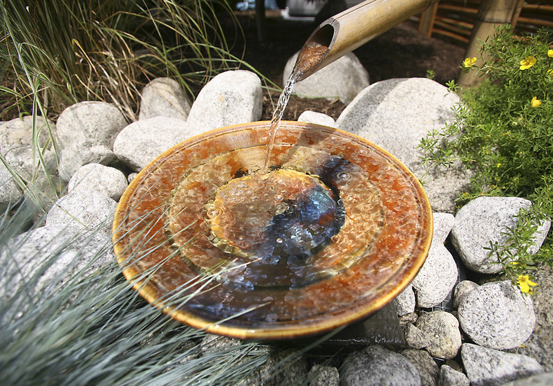 Water flows through a bamboo chute into a water fountain in the Japanese garden at 59 Lafayette St.