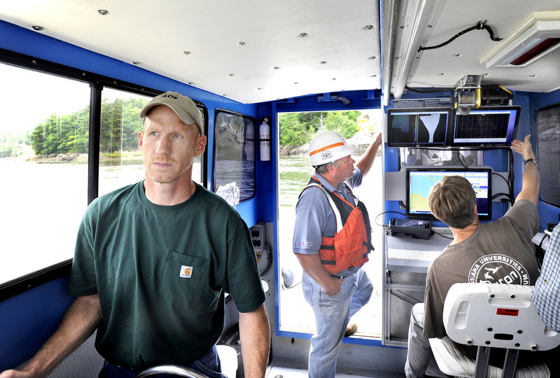 Tom Reis of Substructure pilots a boat that does underwater surveys and inspection of bridges. Behind him, DOT engineer Carl Edwards and Tom Waddington, chief hydrographer, monitor data as they survey the Sheepscot railroad bridge.
