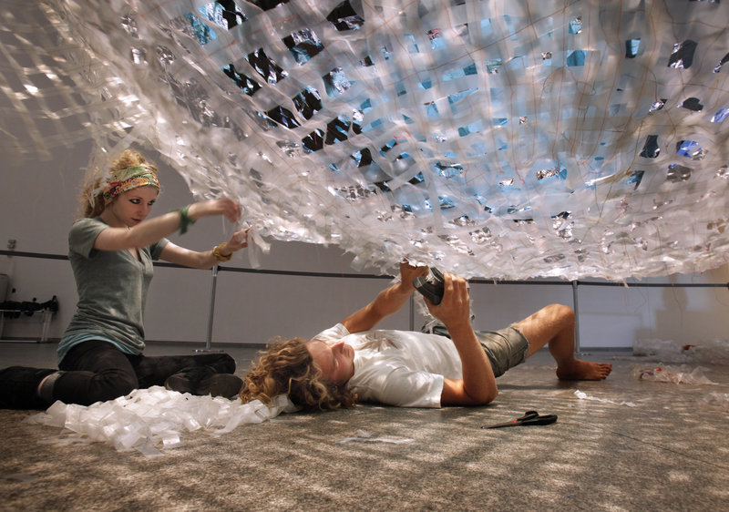 Jenna Breiter, left, and Nate Johnson, assistants to artist Anna Hepler, work on "The Great Haul," made from salvaged plastic that has been sewn together into strips.