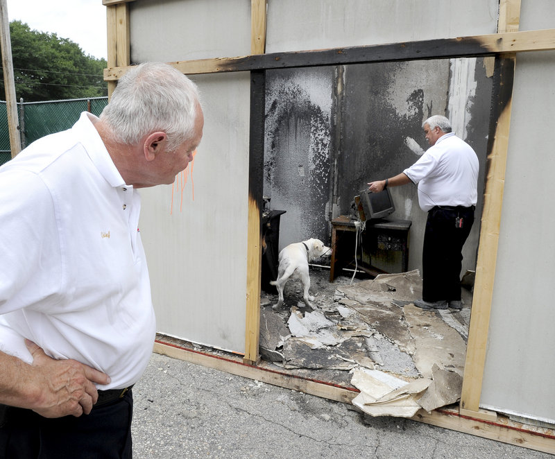 Yarmouth Fire Chief Pat Fairbanks keeps an eye on Deputy Fire Marshal Kurt Lathrop of Bradenton, Fla., as Lathrop and his dog Lucky investigate a staged fire scene. The 14 dogs at this week’s training are all Labradors or Lab mixes and came from places like rescue organizations, shelters and Seeing Eye programs.