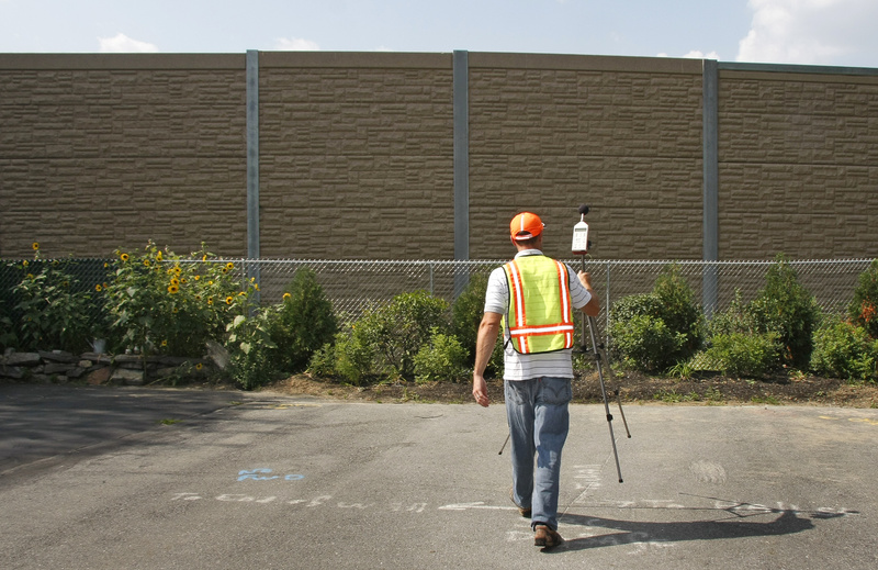 Nate Howard, Maine Department of Transportation noise specialist, sets up a tripod with a sound-level meter on Hobart Street in South Portland to take a reading near the sound barrier built this year along the northbound lanes of I-295 in South Portland