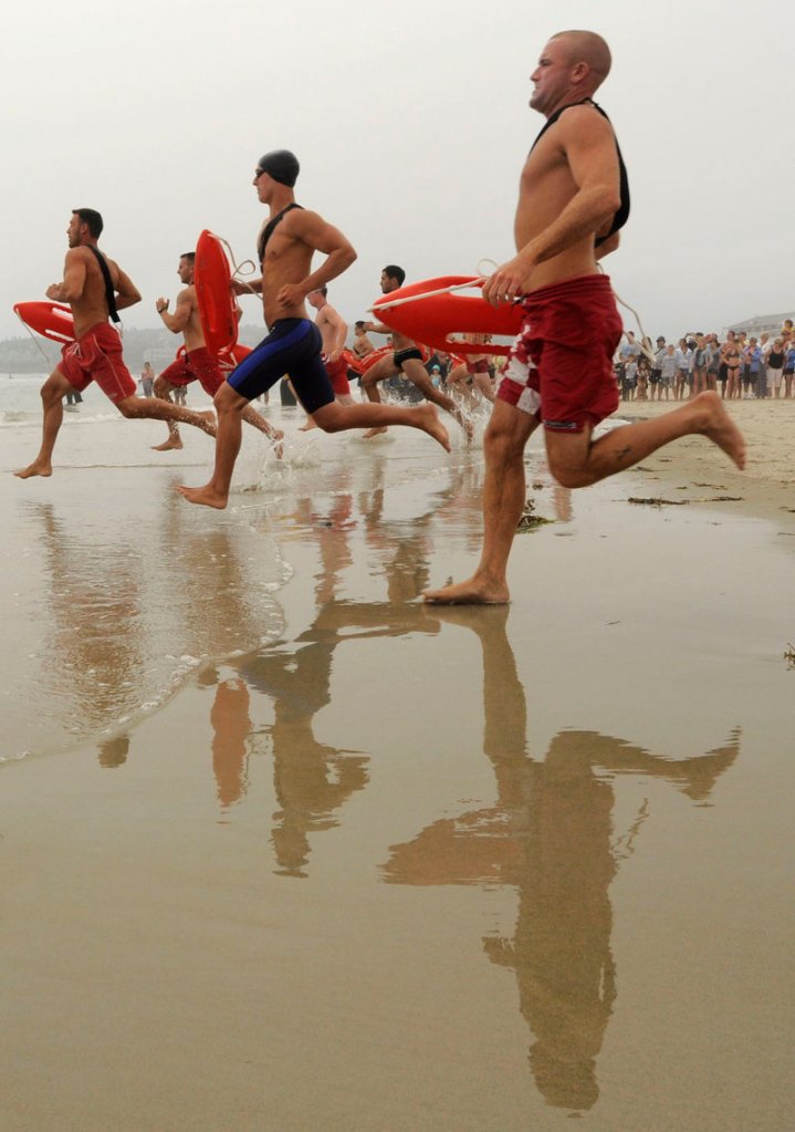 Lifeguards race into the ocean during a surf rescue competition at the Northern New England Lifesaving Championship at Ogunquit Beach on Friday.