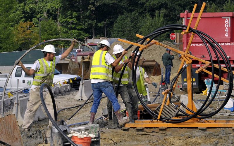 Workers push 1,000 feet of high-density polyethylene pipe into one of 120 500-foot drilled holes that will be one “loop” of the geothermal system being installed to help heat and cool the Portland International Jetport’s expansion when it opens in 2012.