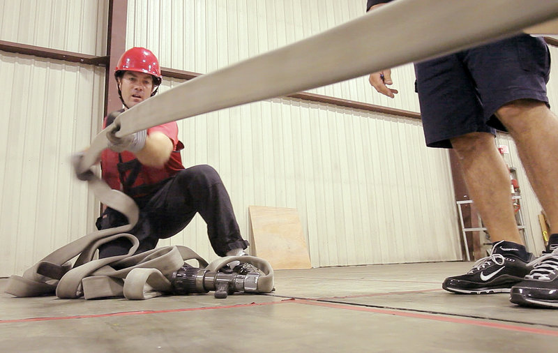Reporter Matt Wickenheiser pulls in a fire hose during a media tryout of the city's Candidate Physical Ability Test, which must be passed by any man and woman who wants to become a Portland firefighter.