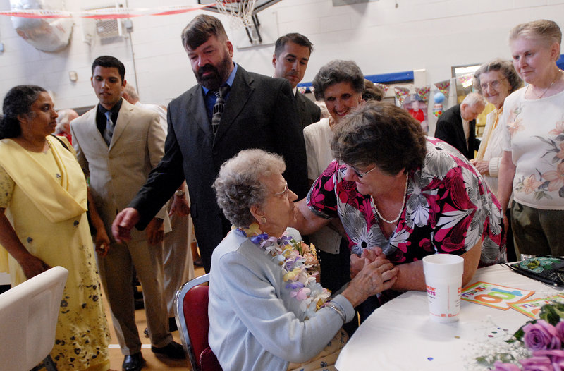 Cora Brown is greeted by friends and family including Kathy Garza of Poland, right, at her surprise 100th birthday party in Portland on Saturday.