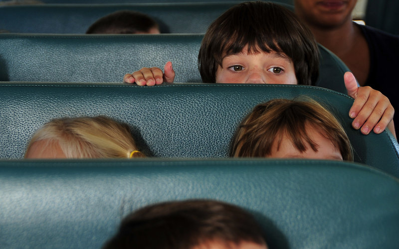 Shane Johnson, 5, looks apprehensive as he peers over the back of a seat during a trial run with his classmates to learn the rules of riding the bus Monday. It was the first day of kindergarten and orientation at the Narragansett School in Gorham.