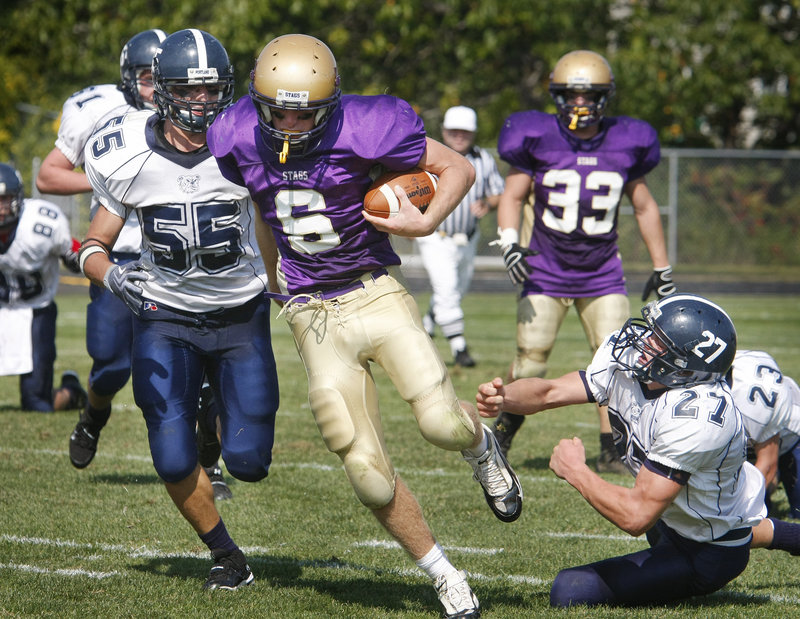 Cheverus quarterback Peter Gwilym breaks away from Max Heller, left, and Caleb Kenney of Portland during a second-half run Saturday in their Western Class A game at Cheverus High.