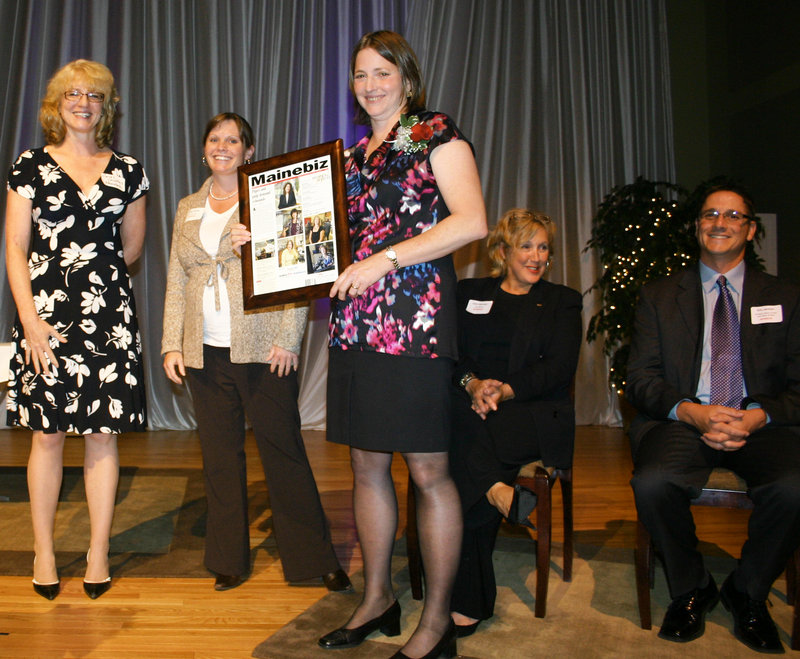 Susan MacKay, president of Zeomatrix, shows off her award, a framed copy of the Mainebiz cover on which she and the other winners appear. Joining her on the stage and presenting the evening’s awards were Mainebiz editor Carol Coultas, Kristy Smith of Preti Flaherty, Jane Harmon of Key Bank and Eric Jermyn of Anthem Blue Cross and Blue Shield.