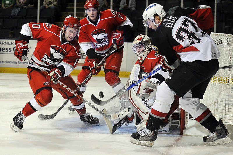 Charlotte’s Jon Matsumoto, left, and Brett Carson, center, fight with Portland’s Matt Ellis for the puck in front of Charlotte goalie Justin Pogge on Monday afternoon at the Cumberland County Civic Center. The Pirates beat the Checkers to improve to 2-0.