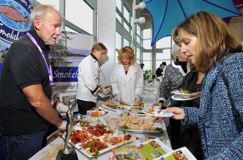Joel Frantzman, left, owner of Sullivan Harbor Farm Smokehouse in Hancock, offers smoked seafood to Michelle Howard of Cape Elizabeth during the Harvest on the Harbor festival at Ocean Gateway on Thursday.