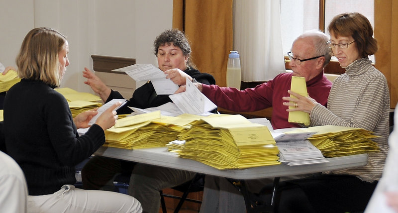 Election workers prepare absentee ballots for scanning into the voting machine in the State of Maine Room at Portland City Hall on Monday. Mainers will choose a new governor, decide races for Congress, the state House and Senate, and vote on three ballot questions today.