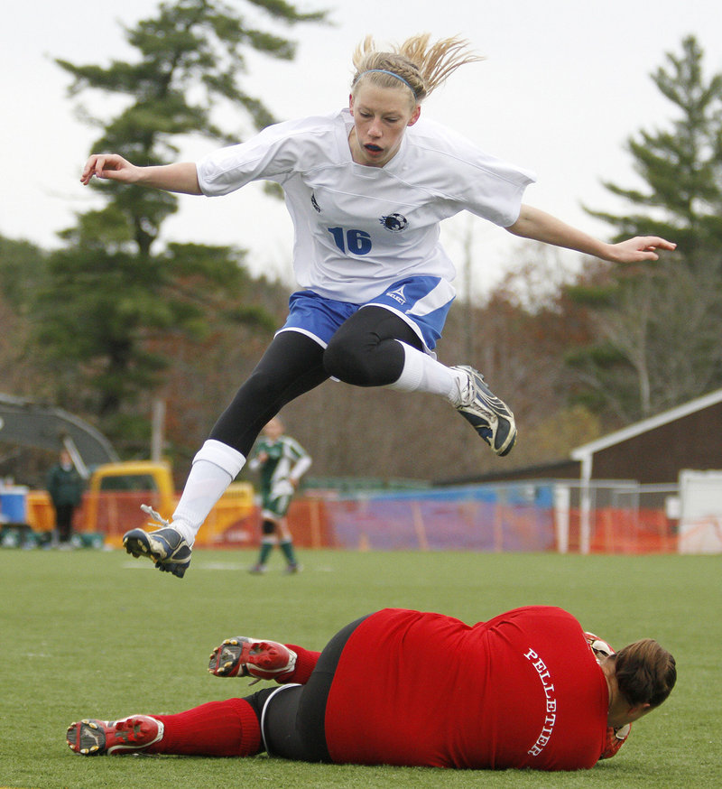 Kara Singleton of Sacopee Valley leaps over Fort Kent goalie Carissa Pelletier, who made a save during the Class C state final at Hampden.