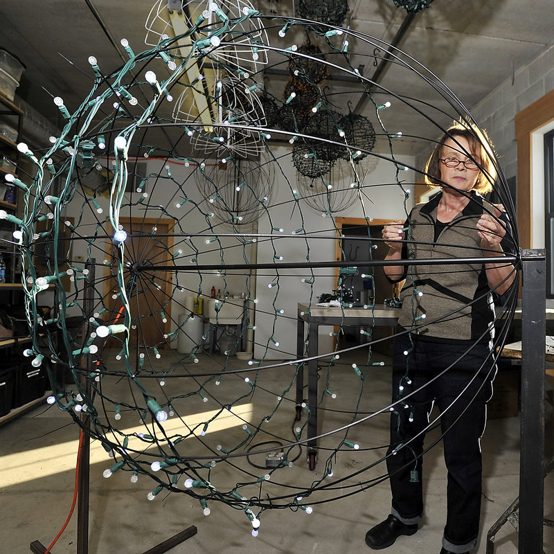 Pandora LaCasse, the artist responsible for designing and installing the seasonal lighting in downtown Portland, at L.L. Bean and in several other communities, attaches strings of lights around a metal rod form, one of hundreds she and her crew have created for the seasonal lighting projects in Maine and beyond.