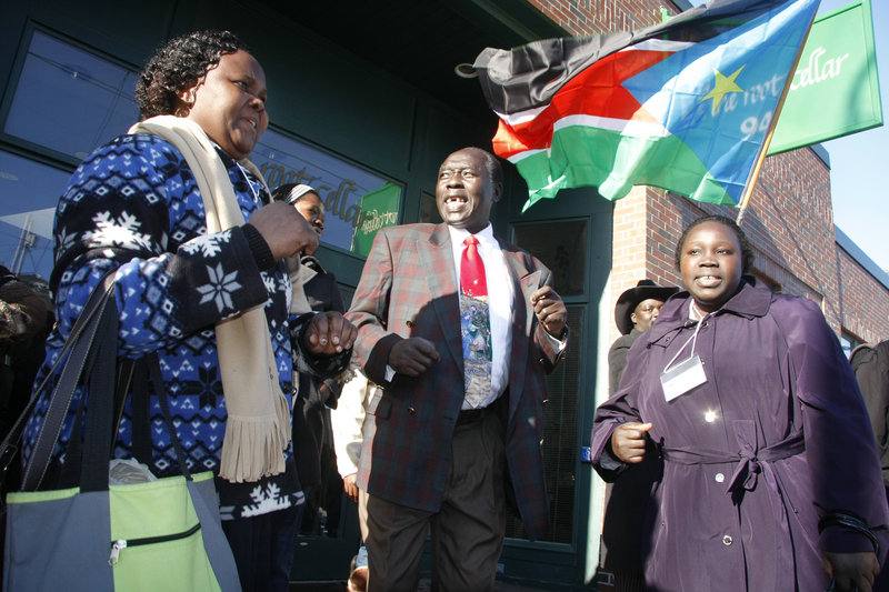 Singing and dancing to a Sudanese song meaning “I Want to Go Home” are, from left, Sabina Apollo, Abwoch Oryem and Teresa Okia, as Sudanese immigrants wait outside The Root Cellar on Sunday to travel to Boston to cast ballots in the country’s national referendum.