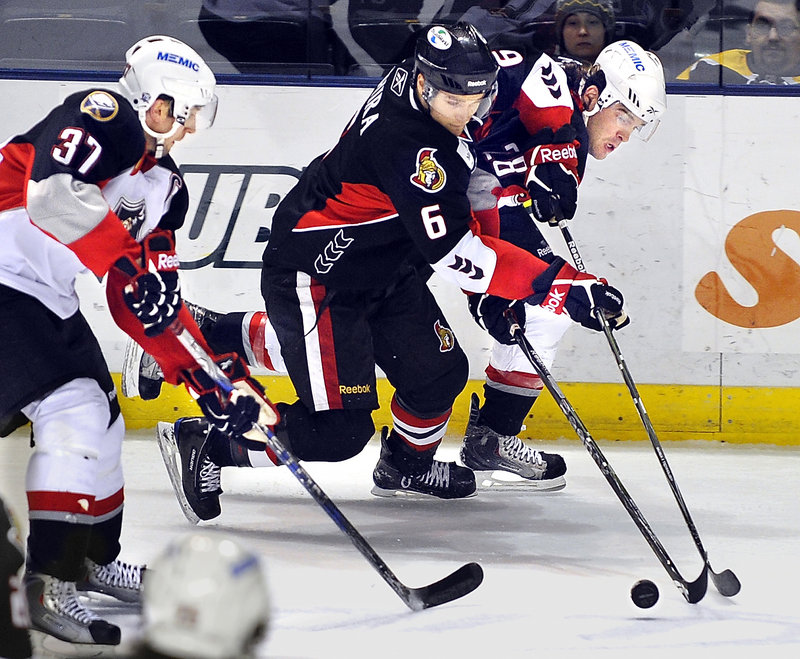 Binghamton’s Craig Schira, center, has the puck knocked away by Portland’s Dennis McCauley, right, as Matt Ellis trails Tuesday night.