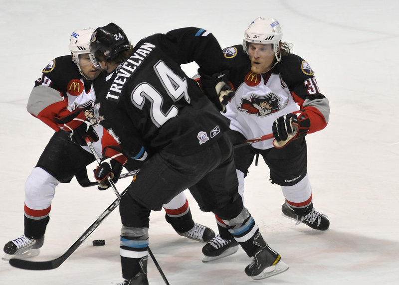 Portland Pirates Brian Roloff, left, and Tim Conboy, right, try to separate Worcester s T.J. Trevelyan from the puck Saturday night at the Cumberland County Civic Center.