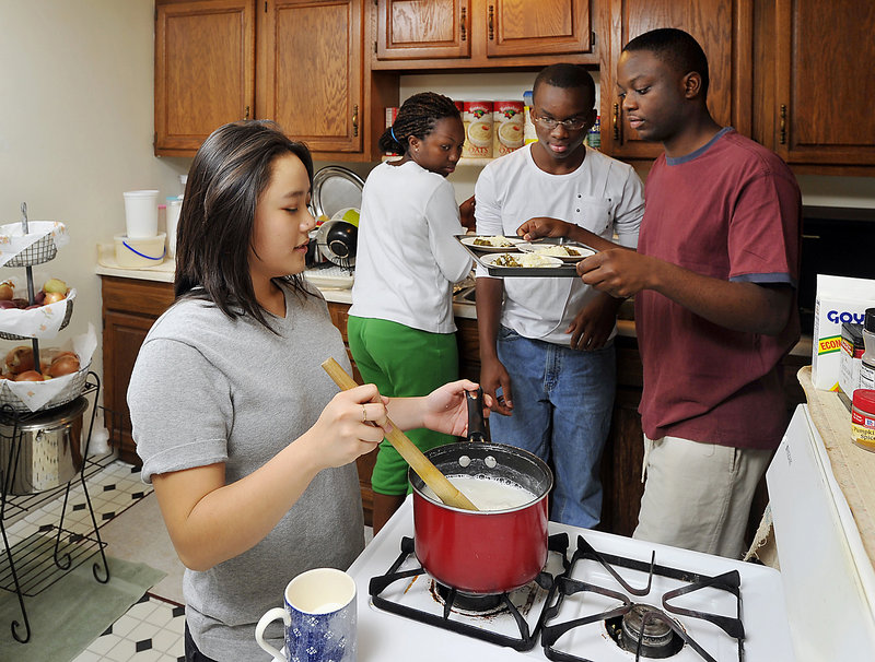 Jenny Tang, left, a sophomore at Williams College, is living in Portland for a month with the Bakunda family, refugees from Burundi, as part of an unusual education program organized by a Portland lawyer. Here, Tang helps make fufu with Lydia, Hugues and Jadot Bakunda.